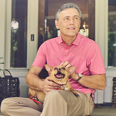 Man sitting on his porch steps holding a small dog