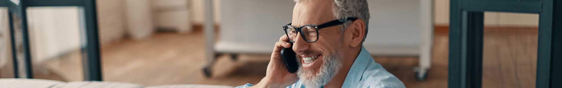 man sitting on his sofa, talking on a phone