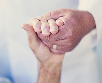 Doctors hand holding an older patients hand